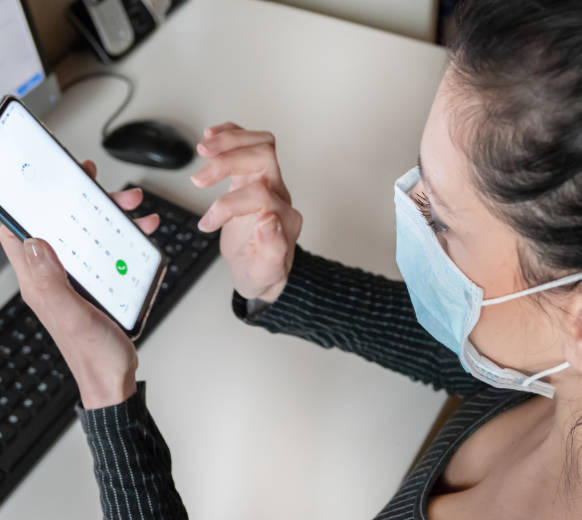 foto de mulher com mascara mexendo no telefone
